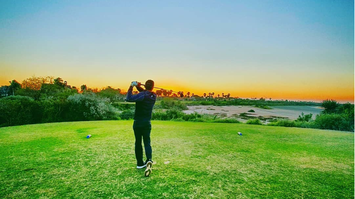 Man swings golf club at south padre island Golf Club at dusk